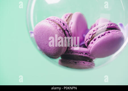 Nahaufnahme von rosa Macarons in glas kugel auf Türkisfarbenem Hintergrund Stockfoto