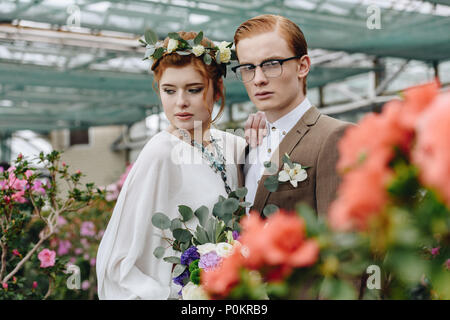 Schöne junge Bräutigam und Braut mit wedding bouquet Gemeinsam im Botanischen Garten Stockfoto