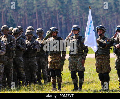 Als Teil der Sabre Streik 18, der rumänischen und der britischen Soldaten machen ein Gruß während dem Abspielen der Nationalhymnen von fünf der teilnehmenden Nationen in Wierzbiny, Polen am 4. Juni 2018. Sabre Streik 18 ist der achte Iteration des langjährigen US-Army Europe - LED-kooperative Arbeit, die Interoperabilität zwischen den Verbündeten und Partnern in der Region zu verbessern. (Michigan Army National Guard Foto von SPC. Alan Prince/freigegeben) Stockfoto