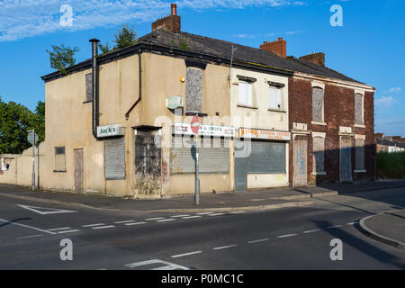 Verfallene Gebäude warten auf Abriss im Abendlicht mit einem blauen Himmel. Stockfoto