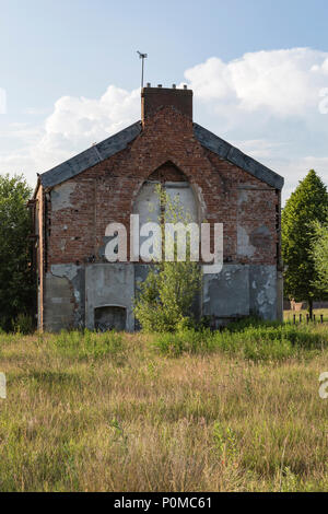 Verfallene Gebäude warten auf Abriss im Abendlicht mit einem blauen Himmel. Stockfoto