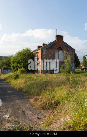 Verfallene Gebäude warten auf Abriss im Abendlicht mit einem blauen Himmel. Stockfoto