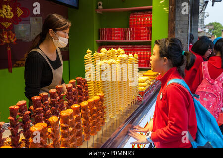 Yangzhou, Jiangsu, China. Junge chinesische Studentin an einem Snack in Dong Guan Straße stehen. Stockfoto