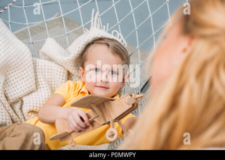 Zugeschnittenes Bild von Mutter und Sohn spielen mit Holz- flugzeug Spielzeug in Hängematte Stockfoto