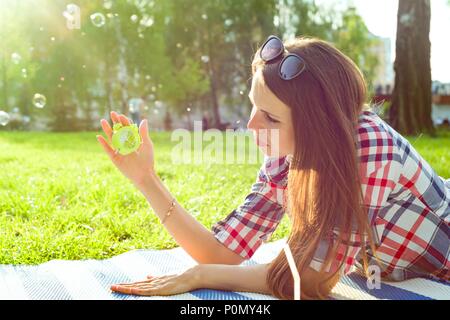 Junge Frau mit Wecker in Ihrer Hand. Hintergrund sunny City Park, kopieren Raum Stockfoto