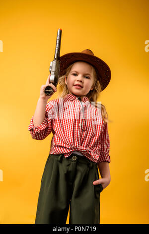 Stilvolle cowgirl in hat mit Gewehr, isoliert auf Gelb Stockfoto