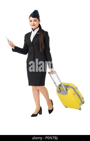 Junge Stewardess mit Koffer mit Smartphone isoliert auf weißem Stockfoto