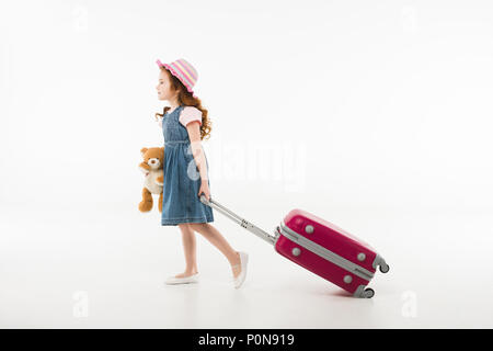 Kleine stilvolle Tourist in Hut mit Teddybär und Koffer auf Weiß, Travel Concept isoliert Stockfoto