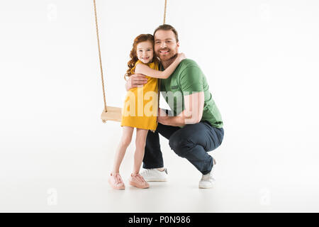 Tochter in der Nähe von Swing und umarmt Vater isoliert auf weißem Stockfoto