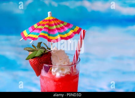 Nahaufnahme eines Frosty frozen Strawberry Daiquiri Cocktail mit einem bunten Regenschirm und Schlagsahne Stockfoto