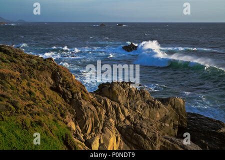 Abendlicht glühen auf Wellen und ICE-Werk auf den Klippen bei Garrapata State Park entlang der Kalifornischen Küste von Big Sur. Stockfoto