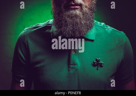 7/8 Schuß von bärtigen Mann mit grünen Poloshirt mit Kleeblatt Symbol Stockfoto