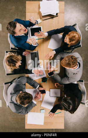 Ansicht von oben von wütenden Unternehmer und Mitarbeiter bei Tisch mit digitalen Geräte, Dokumente Stockfoto