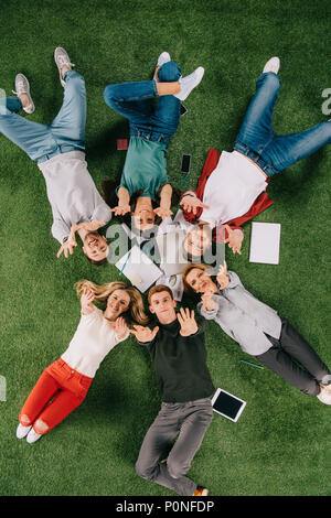Ansicht von oben der glücklichen Geschäftsleute mit den Armen bis zur Festlegung auf Gras Stockfoto