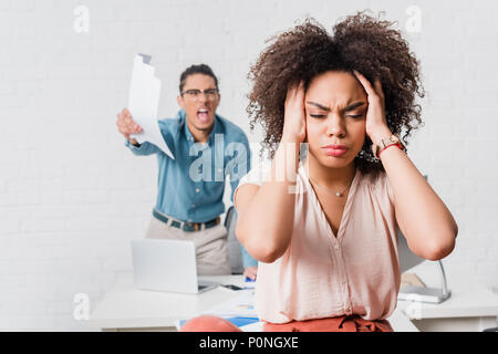 Frau, die unter Stress leiden, weil der verärgerten männlichen Kollegen im Büro Stockfoto