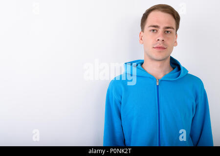 Jungen gutaussehenden Mann trägt blaue Kapuzenjacke vor weißem Hintergrund Stockfoto