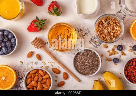 Zutaten für ein gesundes Frühstück - Müsli, Honig, Nüsse, Beeren, Früchte, Ansicht von oben Stockfoto
