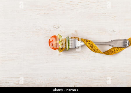 Frischer Salat auf einer Gabel, Maßband, Ansicht von oben. Das Konzept der Ernährung, gesundes Essen Stockfoto