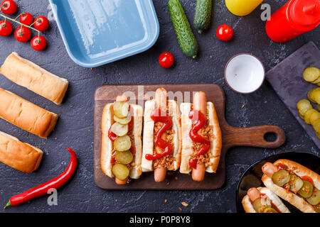 Bild oben auf Brötchen mit Wurst auf Schneidebrett, auf Tabelle mit Gurken Stockfoto