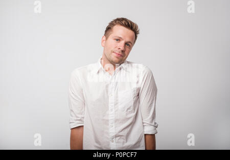 Europäischen Mann bescheiden und peinlich, auf grauem Hintergrund. Stockfoto