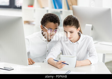 Portrait der multikulturellen Studenten, Aufgabe zusammen, beim Sitzen am Tisch in der Klasse Stockfoto