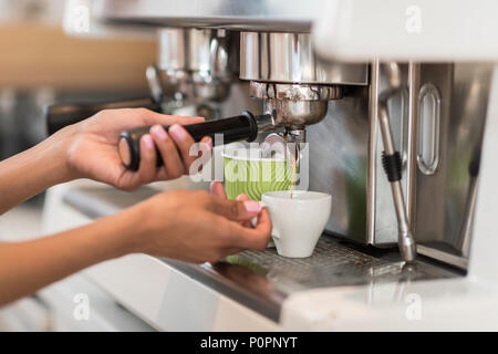 7/8 shot der weiblichen Barista mit Kaffeemaschine und Kaffee im Cafe Stockfoto