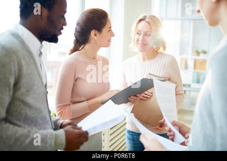 Gruppe positiver Innenarchitekten versammelten sich im geräumigen Großraumbüro und den Austausch von Ideen in Bezug auf gemeinsame Projekt, lens flare Stockfoto