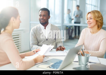 Arbeitstreffen mit voller Geschwindigkeit: multi-ethnischen Team der weißen Arbeiter am Tisch von Großraumbüro sitzen und Brainstorming über gemeinsames Projekt Stockfoto