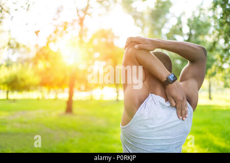 Rückansicht des athletischen jungen afrikanischen amerikanischen Sportler dehnen in Park Stockfoto