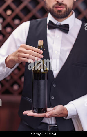 Portrait von Stattlichen sommelier Holding Flasche Wein im Keller Stockfoto