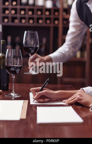 Zwei Sommeliers, männlichen und weiblichen Weinprobe Rotwein und sich Notizen auf degustation Karte Stockfoto