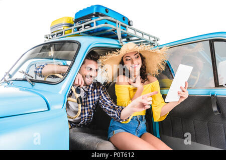 Junge glückliches Paar von Reisenden im Auto sitzen und auf Karte isoliert auf weißem Stockfoto