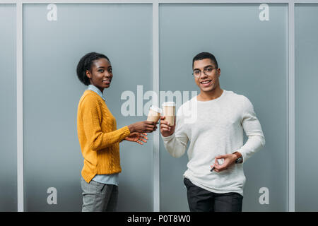 Junge afrikanische amerikanische Geschäftspartner klirren Einweg Tassen Kaffee Stockfoto