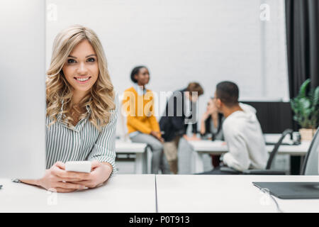 Junge schöne Frau mit im Büro smartphone Stockfoto