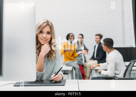 Junge Designer Zeichnung mit Tablet mit unscharfen Partner auf Hintergrund Stockfoto