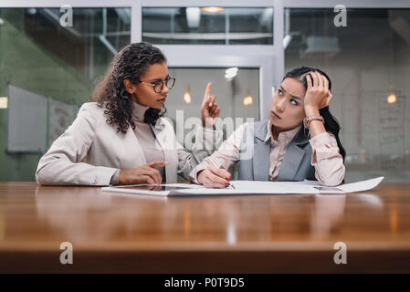 Müde und schwere multiethnischen Unternehmerinnen Arbeiten mit Dokumenten in Office Stockfoto
