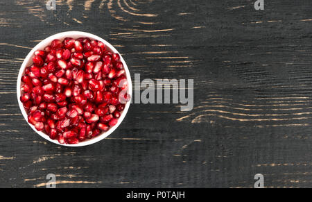 Weiße Schüssel mit Granatapfel Samen auf eine leere Holz- Hintergrund, Ansicht von oben gefüllt Stockfoto
