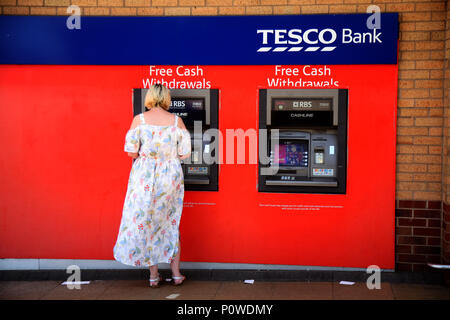 Dame in einem der zwei Geldautomaten am Supermarkt Tesco an Undergate Rd, Dinnington, Sheffield S25 2PF Stockfoto