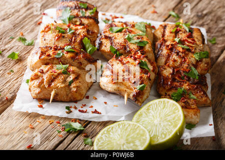 Afghanische Essen: Hühnchen Kebab, mariniert in einen Joghurt Kreuzkümmel Sauce close-up auf Papier auf Tisch. Horizontale Stockfoto