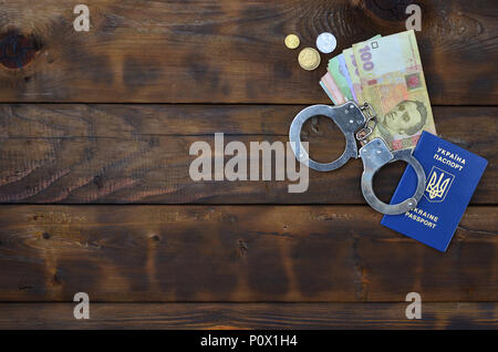 Ein Foto von einem ukrainischen ausländischer Reisepass, eine bestimmte Menge von ukrainischen Geld und Polizei Handschellen. Konzept der illegalen Ergebnis der Ukrainischen citiz Stockfoto
