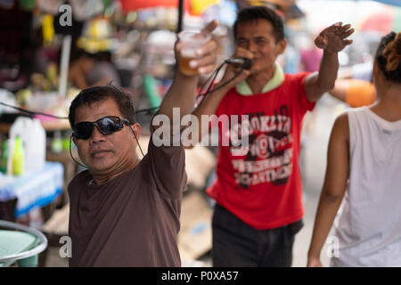 Filipino Mann singt auf dem Karaoke während Freunde trinken neben ihm. Stockfoto