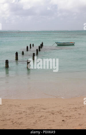 Sandige Küste, zerstörte Steg und Boot. Anse de Sent-An, Pointe-à-Pitre, Guadeloupe Stockfoto