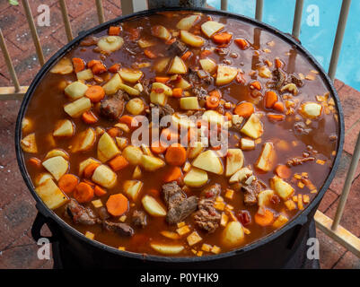 Ungarisches Rindergulasch in einem großen gusseisernen Topf gekocht, Zutaten Paprika, Rind, Karotten und Kartoffeln. Stockfoto