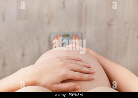 Closeup schwangere Frau auf Skalen, die Ansicht von oben. Kontrolle der Gewichtszunahme in der Schwangerschaft Zeit Stockfoto