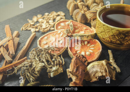 Getrocknete Kräuter und Ginseng, Close-up der thailändischen Kräutern und Ginseng auf Holzboden. Scheiben trocknet Root für ein Kraut Saft auf der dunklen Tisch machen. Stockfoto