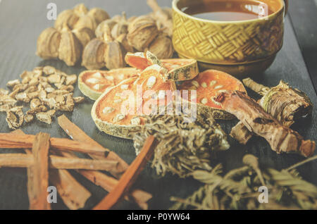 Getrocknete Kräuter und Ginseng, Close-up der thailändischen Kräutern und Ginseng auf Holzboden. Scheiben trocknet Root für ein Kraut Saft auf der dunklen Tisch machen. Stockfoto