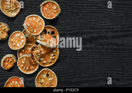 Getrocknete Kräuter und getrockneten bael Frucht, Ansicht von oben von bael trocken auf dem Holzboden, Scheiben von bael Frucht für bilden bael Saft auf der dunklen Tisch. Stockfoto
