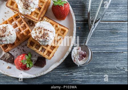 Belgische Waffeln mit Vanilleeis, frischen Erdbeeren und Schokolade. Leckeres Frühstück. Ansicht von oben Stockfoto