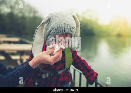 Eine Mutter helfen ihr kleiner Sohn Schlag seine Nase Stockfoto