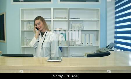 Weibliche Krankenschwester im Krankenhaus Rezeption Entgegennehmen von Anrufen und Terminplanung Patienten Termine Stockfoto